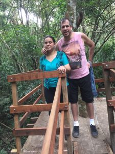 Atena e Marlon em pé na casinha da árvore com árvores e folhagens